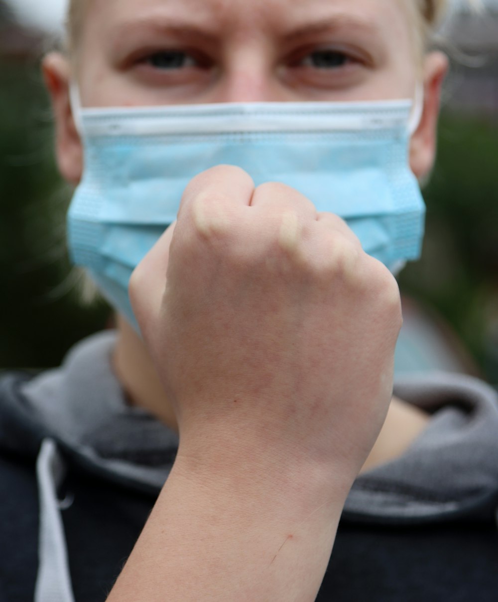 Person in schwarzem Kapuzenpullover mit blauem Plastikbehälter