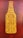 A graphic stylized as a beer bottle with the text 'Good People Drink Good Beer' written in bold, uppercase letters. The design features a mustard yellow bottle shape against a textured, dark reddish-brown background.