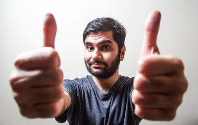 man in gray crew neck shirt making thumbs up excited teams background