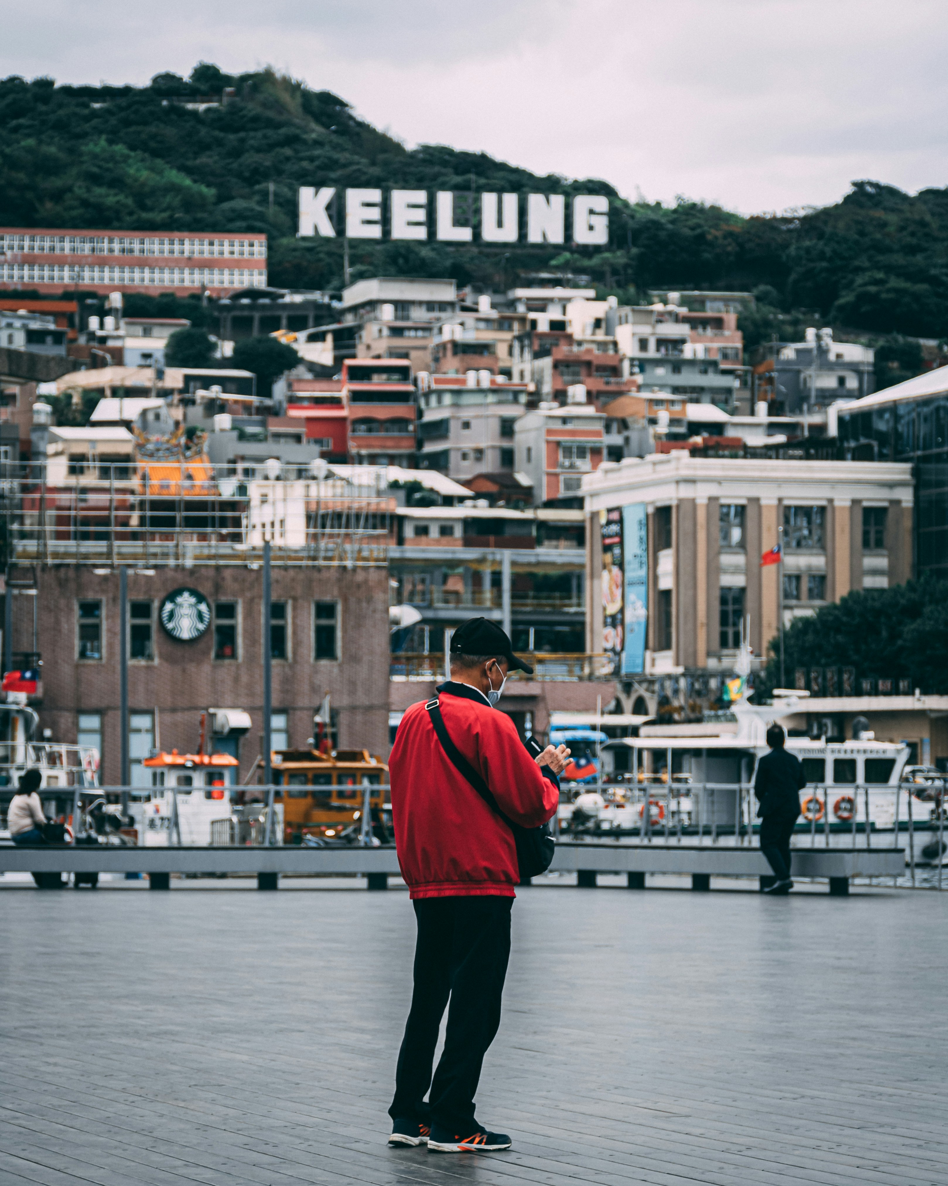 man in red jacket standing near body of water during daytime