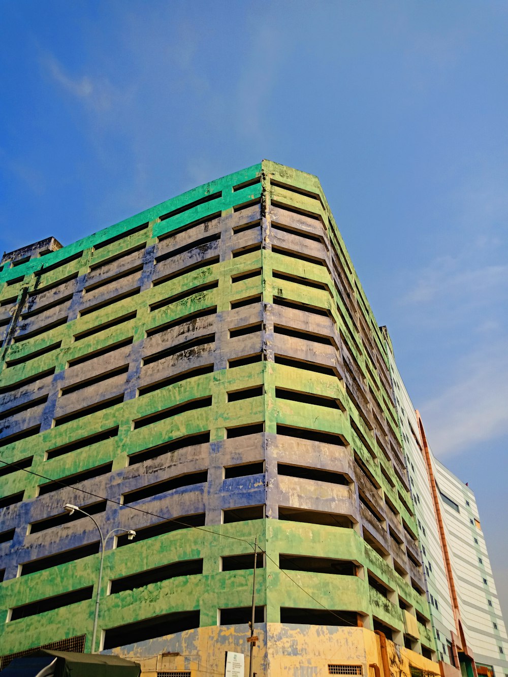 낮 동안 푸른 하늘 아래 녹색과 흰색 콘크리트 건물