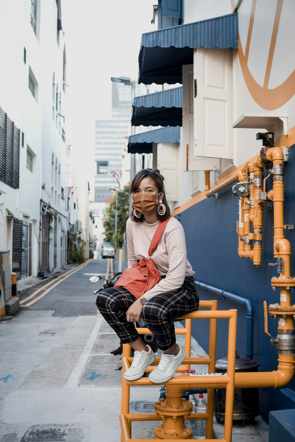 woman in red cardigan sitting on yellow metal bench during daytime