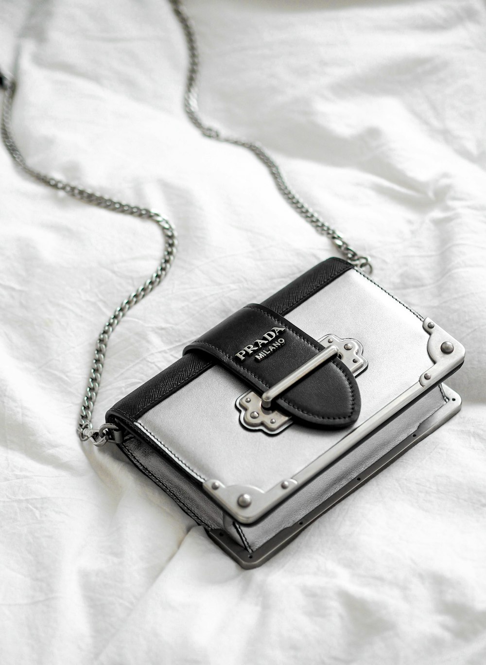 black leather sling bag on white textile