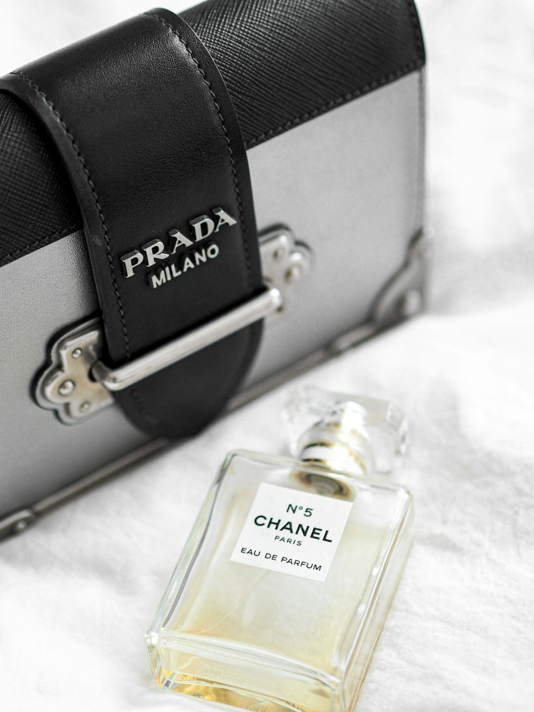 clear glass perfume bottle beside black leather bag
