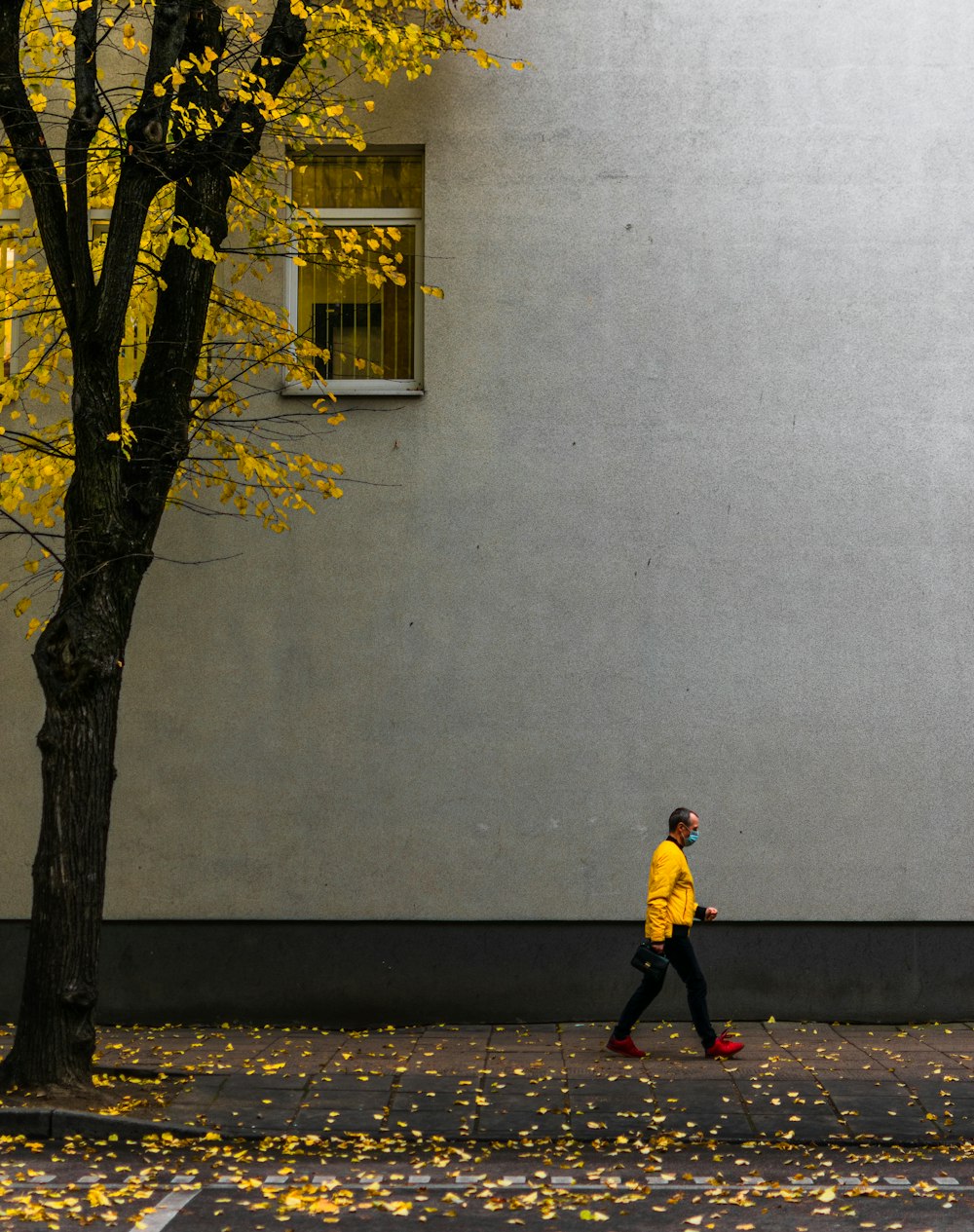 man in yellow jacket and black pants standing beside tree