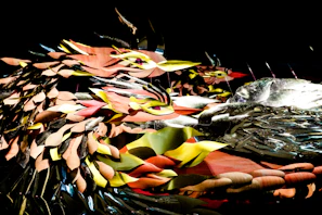 A striking mixed-media piece featuring layered textures of leaves, feathers, and human silhouettes, evoking the spirit of nature’s resilience.