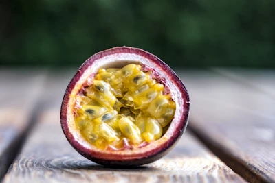 Passion fruits halved to show their golden, juicy seeds against a soft white backdrop.