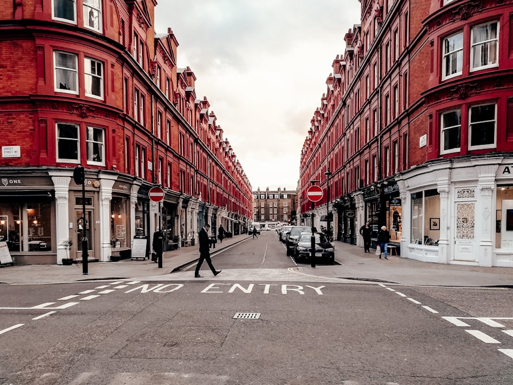 people walking on street between red concrete buildings during daytime