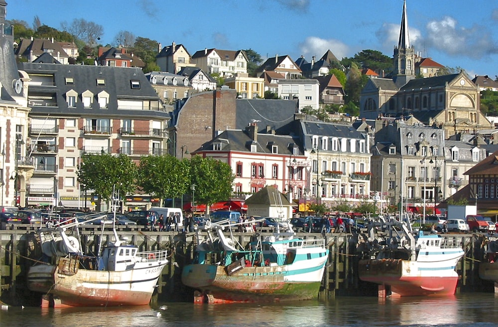 white and red boat on dock near buildings during daytime