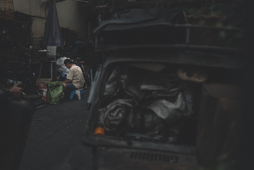 man in white long sleeve shirt and green pants sitting on black car