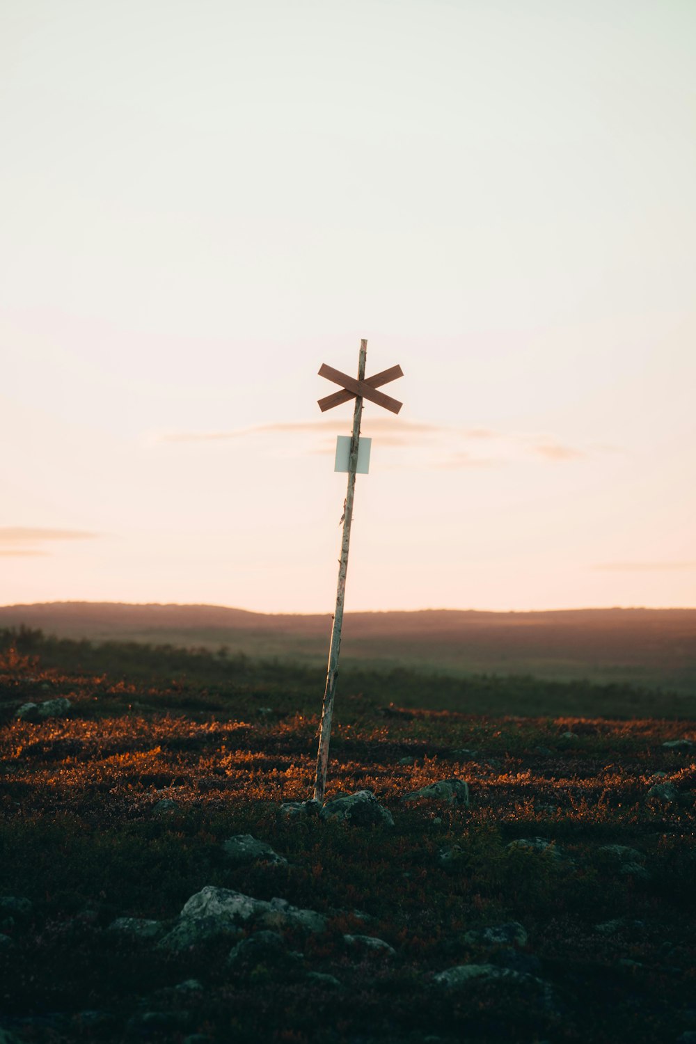 brown cross on brown grass field under white sky during daytime