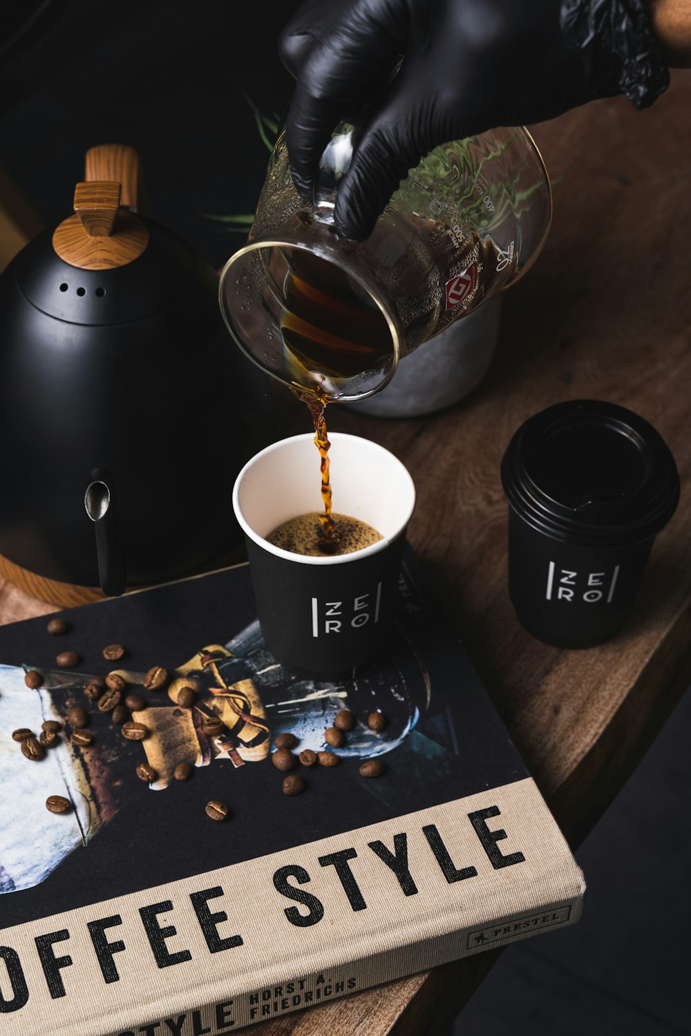 clear glass mug with coffee beside coffee beans and coffee beans on table