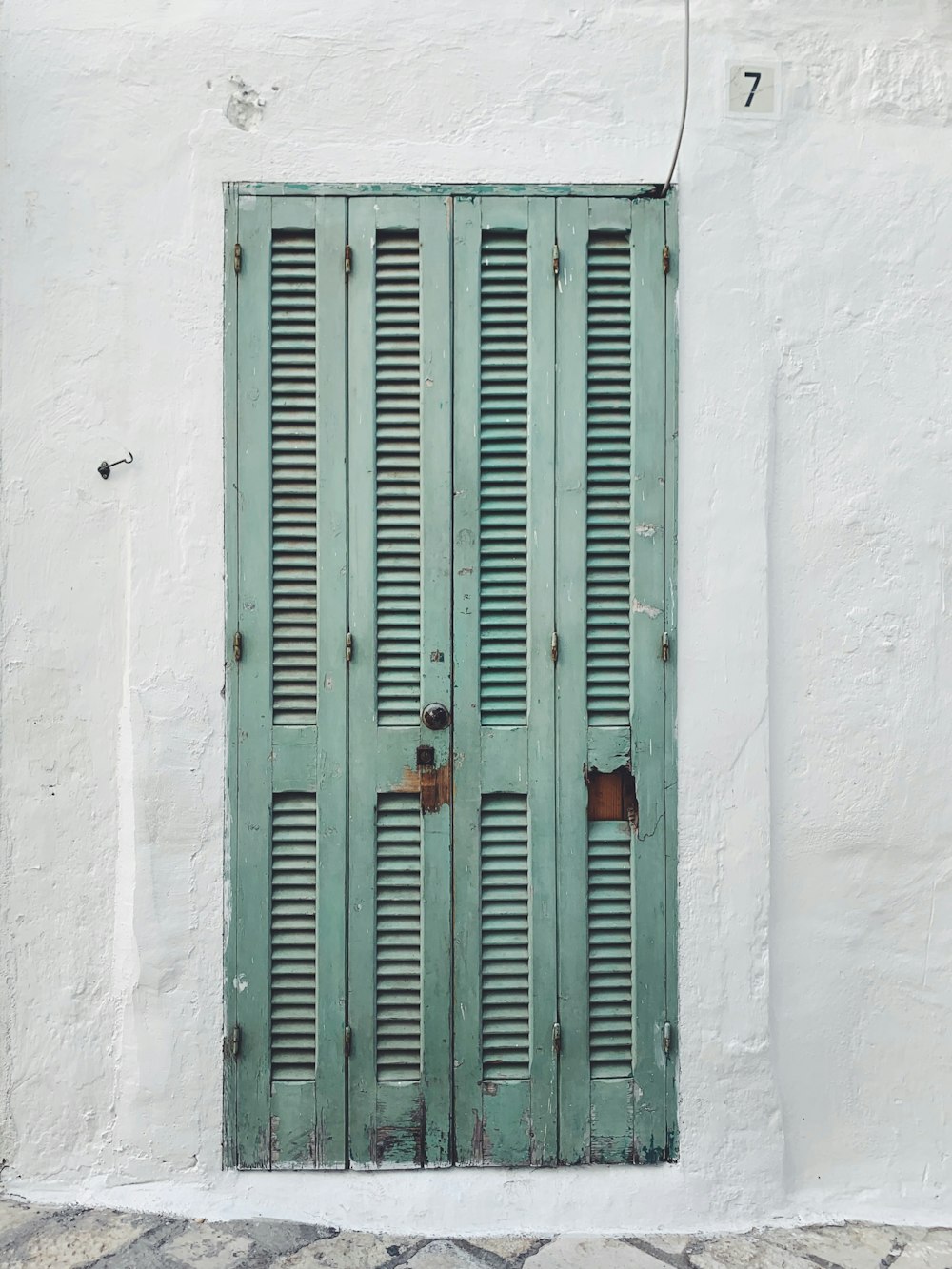 puerta de madera azul sobre pared de hormigón blanco