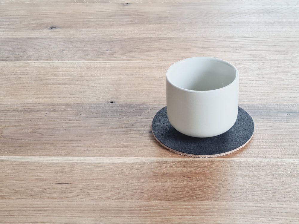 una tazza bianca seduta sopra un tavolo di legno