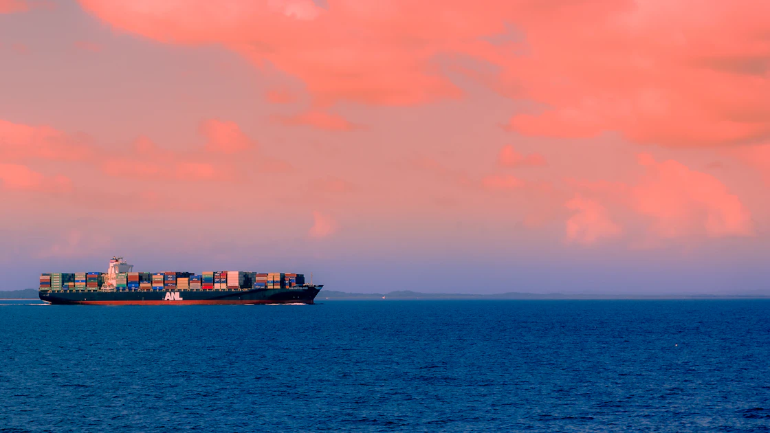 A loaded cargo ship at sea under a cloudy sky off Moreton Island, Australia.
