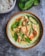 A vibrant plate of Thai green curry with fresh basil and colorful vegetables.