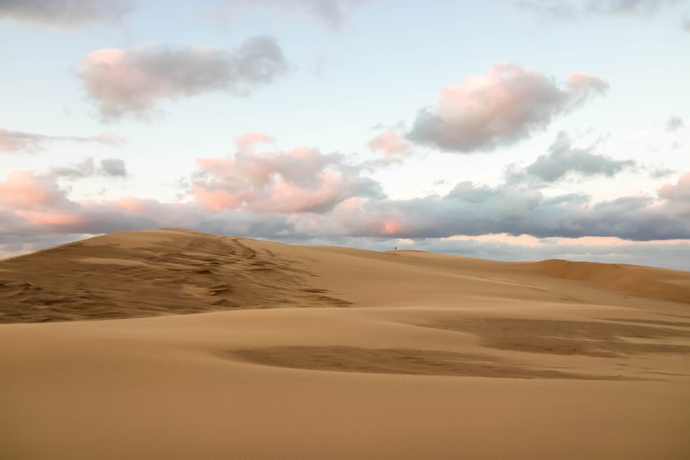 brown sand under white clouds during daytime