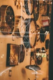 A wall filled with various styles of clocks, ranging from modern to classic designs. The lighting gives a warm, vintage ambiance. Some clocks are round, others are square, and there is a visible price tag indicating a sale. The foreground shows glass reflections.