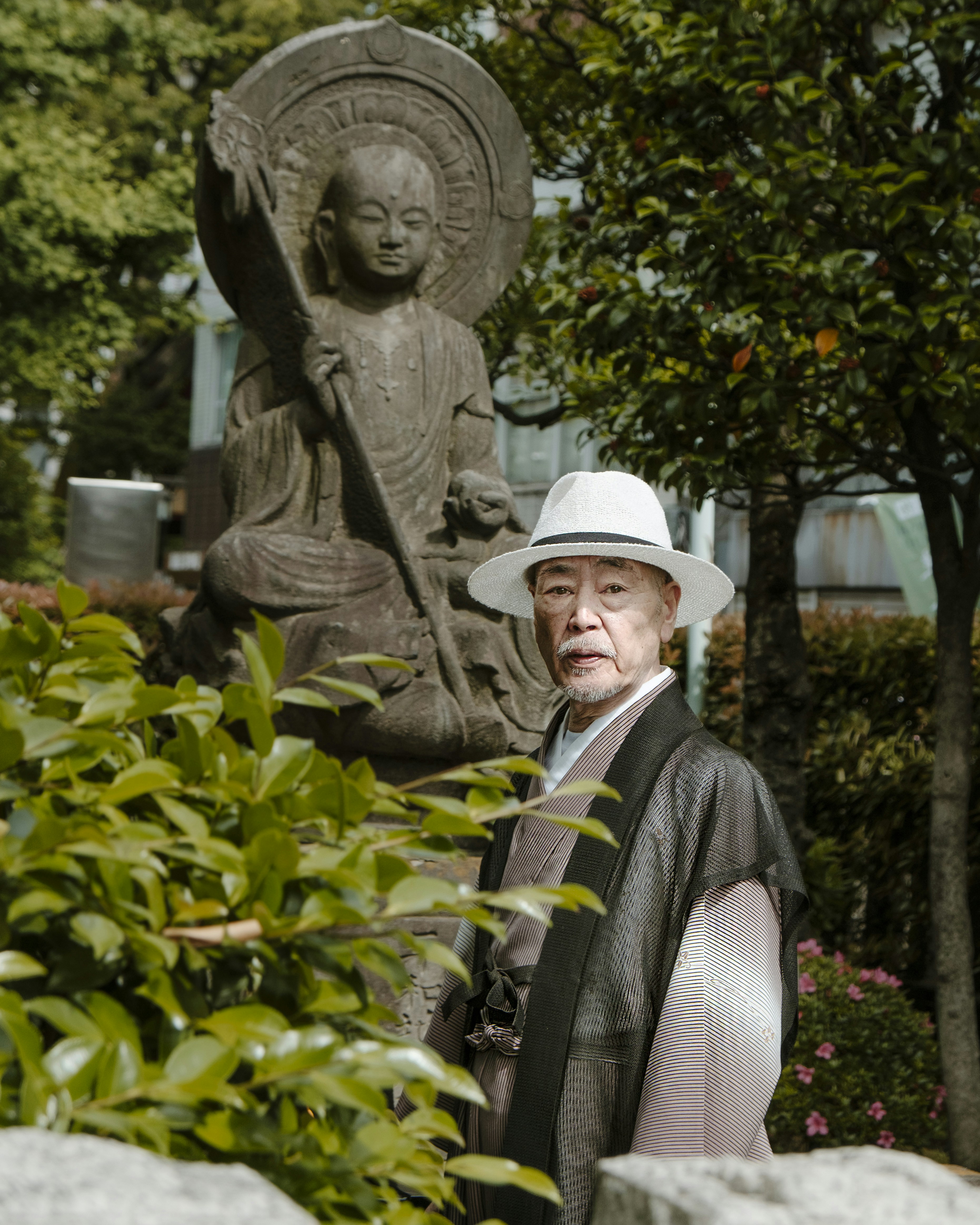 woman in white hat and black and white stripe long sleeve shirt standing near green plants