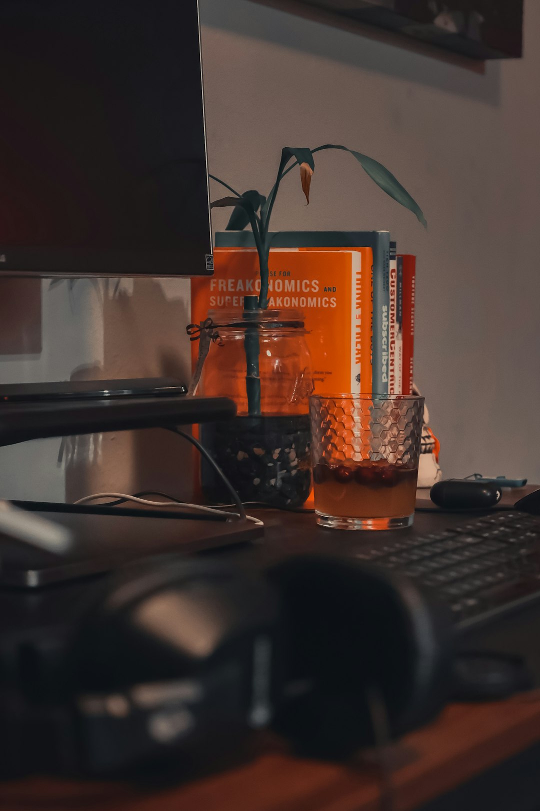 clear drinking glass beside black computer keyboard on brown wooden desk