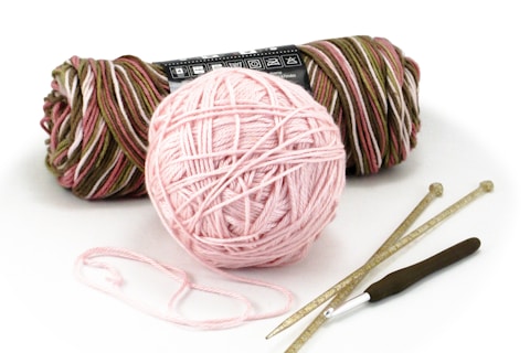 pink yarn ball and white plastic spoon