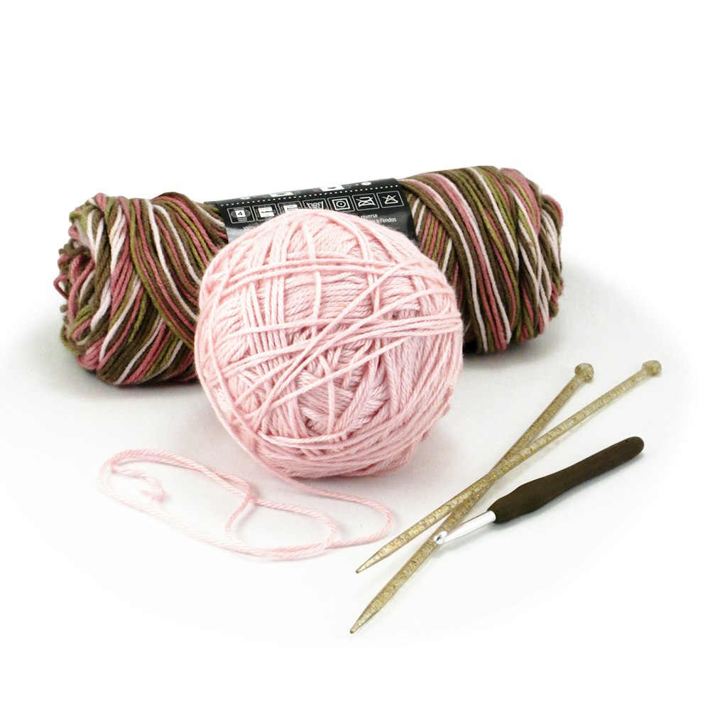 pink yarn ball and white plastic spoon