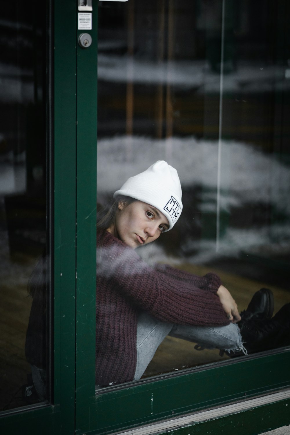 woman in blue sweater and white fitted cap sitting on green wooden bench