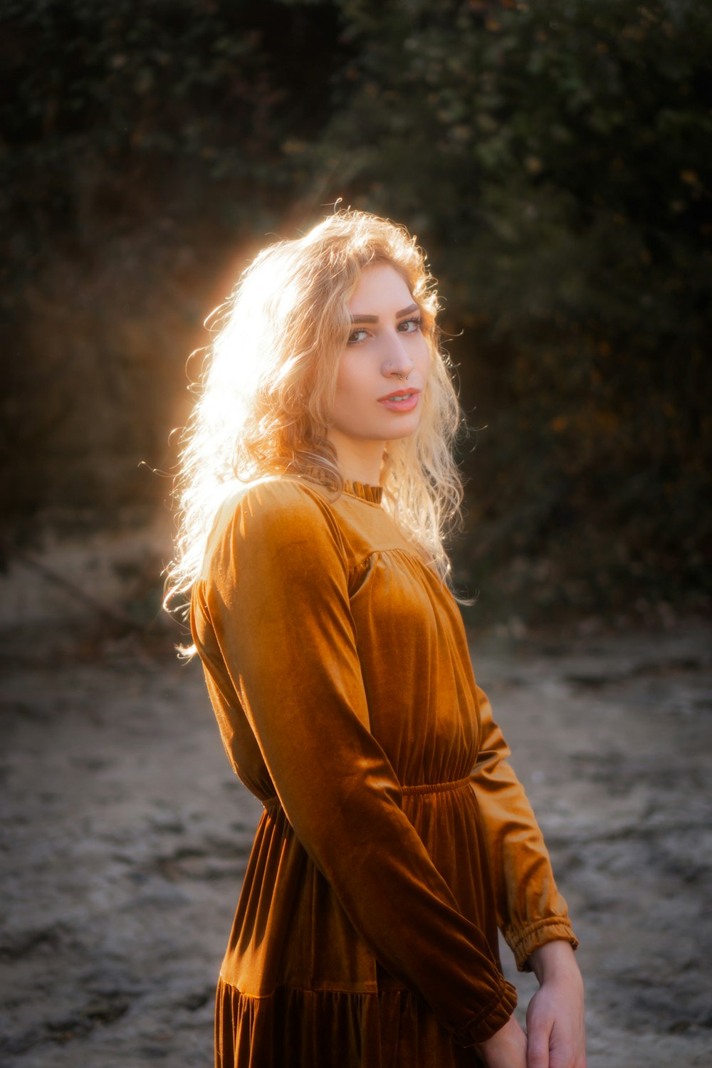 woman in brown leather jacket standing on brown dirt road during daytime