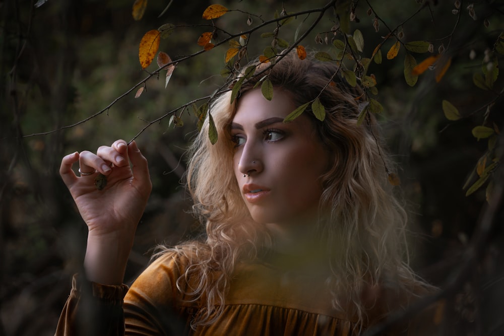 woman in brown and black long sleeve shirt holding yellow leaves