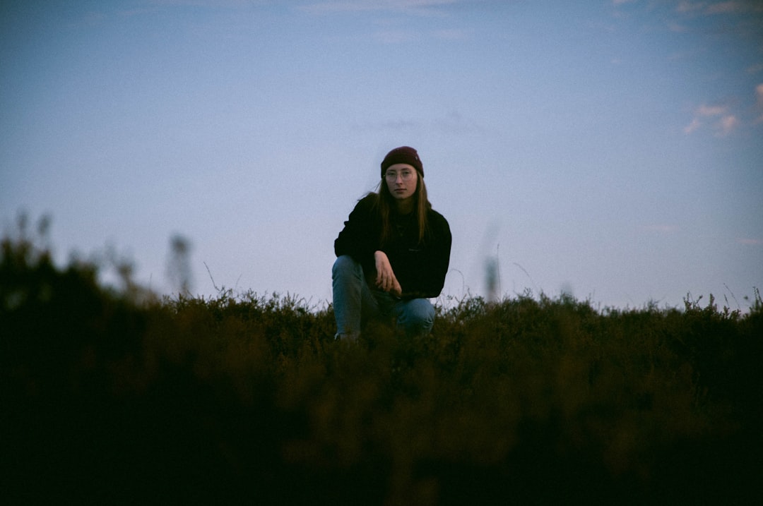 woman in black long sleeve shirt sitting on green grass field