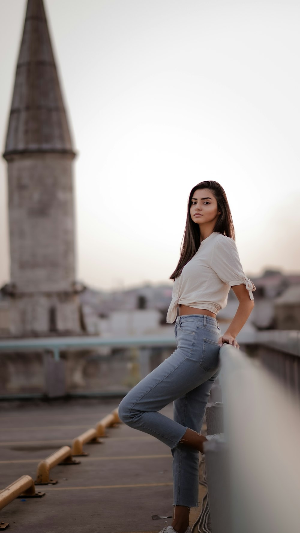 woman in white t-shirt and blue denim jeans standing near white concrete building during daytime