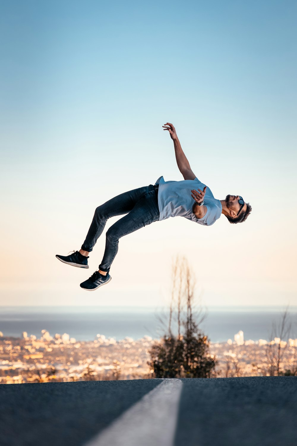 man in blue t-shirt and blue denim jeans jumping on air during daytime
