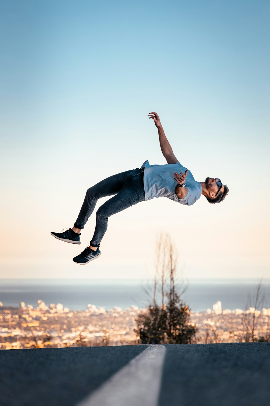 man in blue t-shirt and blue denim jeans jumping on air during daytime