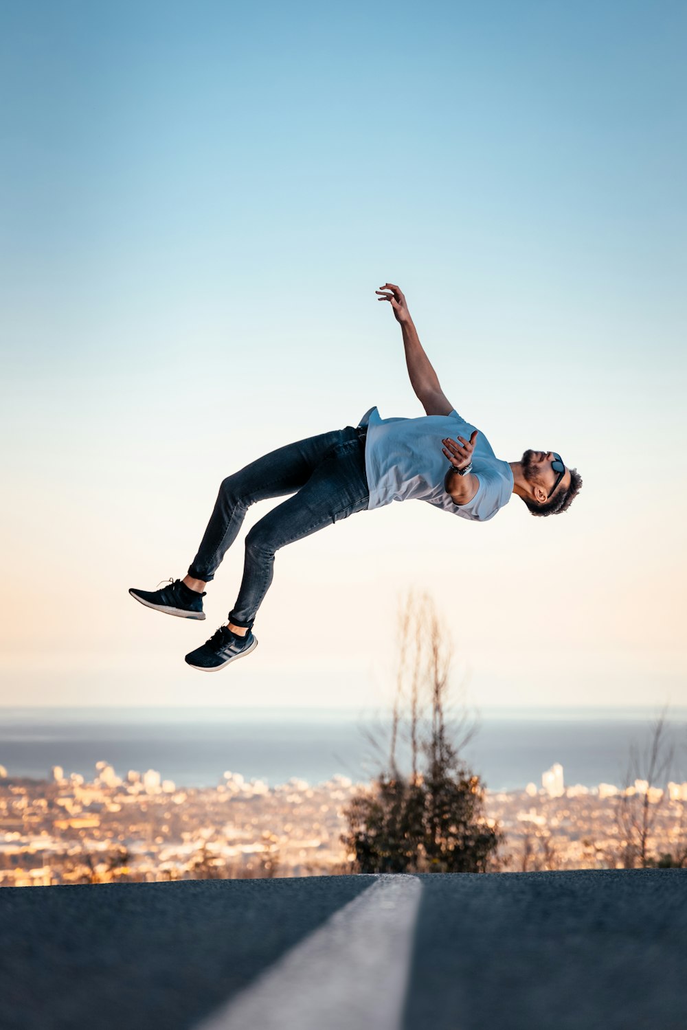 Hombre con camiseta azul y jeans de mezclilla azul saltando en el aire durante el día