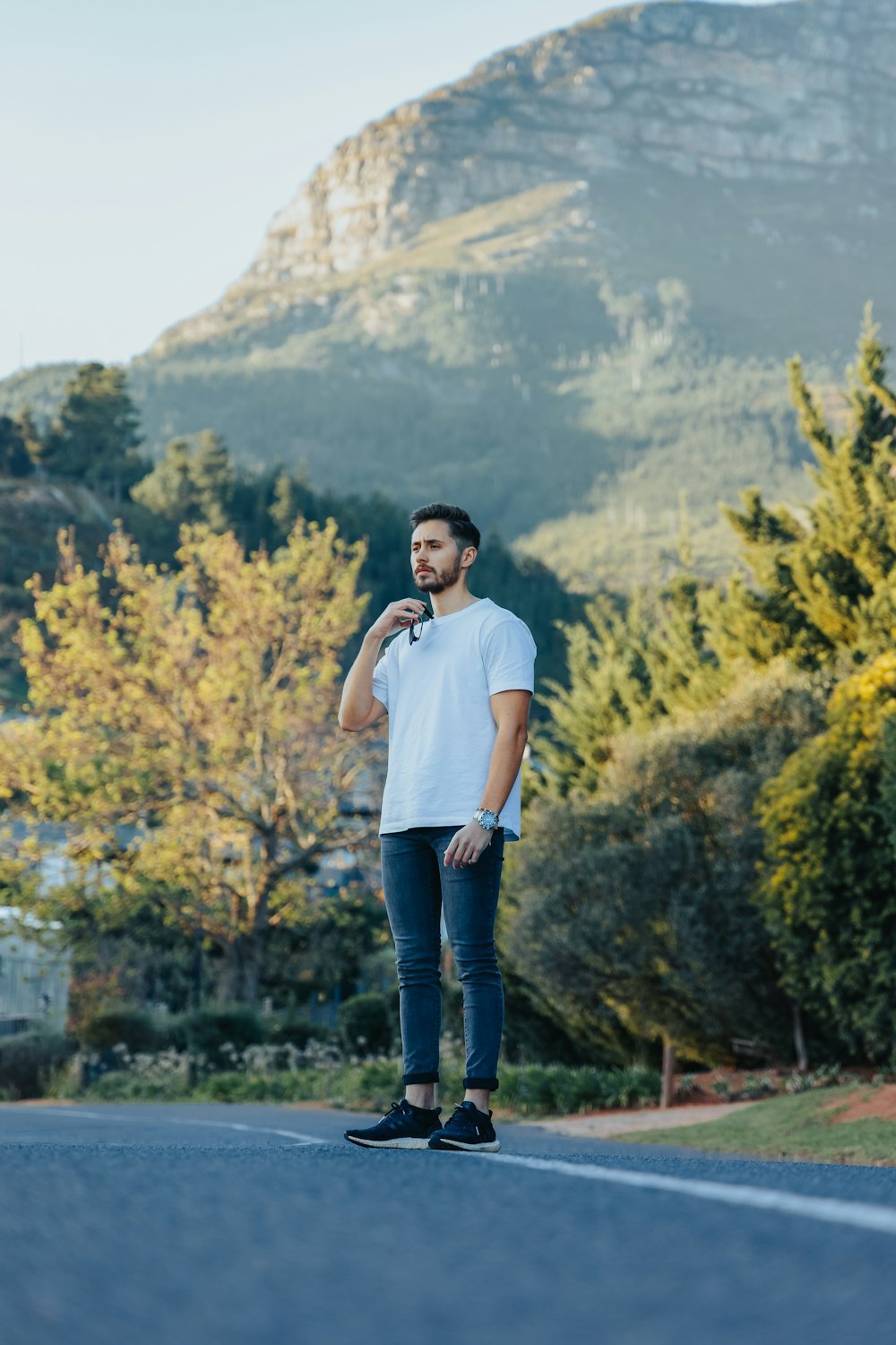 uomo in t-shirt girocollo bianca e jeans blu in denim in piedi sul campo in erba verde