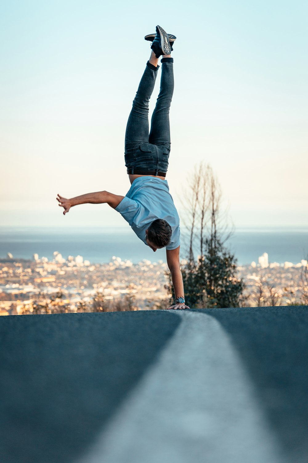 woman in blue denim jeans and white shirt standing on gray concrete wall during daytime