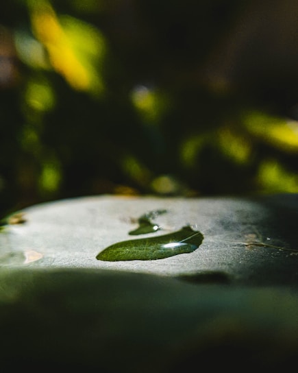 Close-up of a smooth liquid foundation drop on a glass surface reflecting soft light