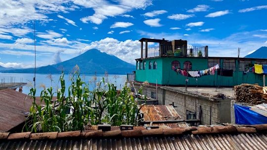 green and blue wooden house near body of water under blue sky during daytime in Santa Clara La Laguna Guatemala