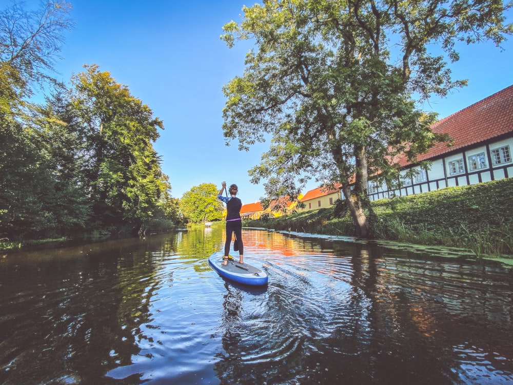 hombre con camisa azul montando en un bote azul en el río durante el día