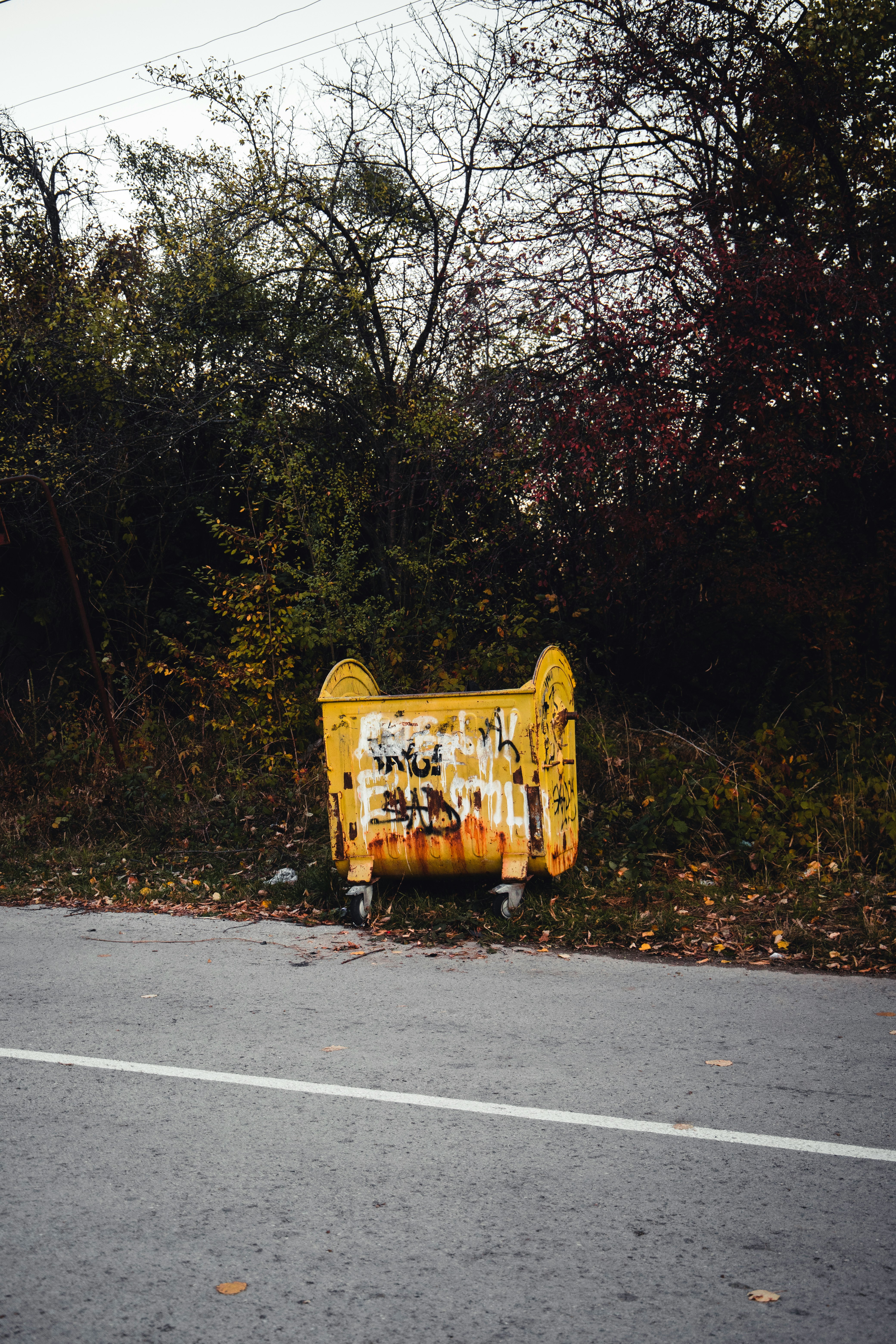 yellow and black trash bin on gray asphalt road