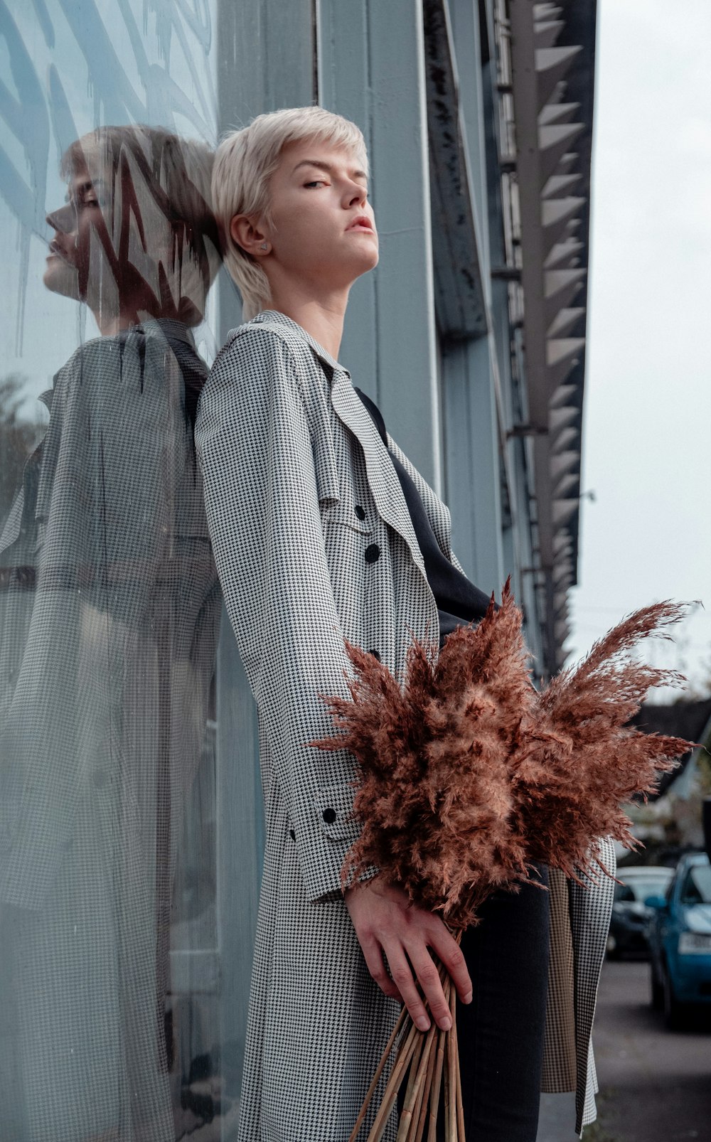 woman in gray coat standing near red flowers