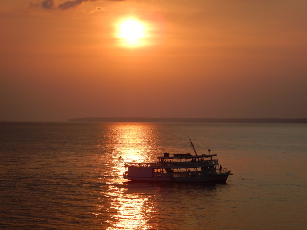 navio branco e vermelho no mar durante o pôr do sol