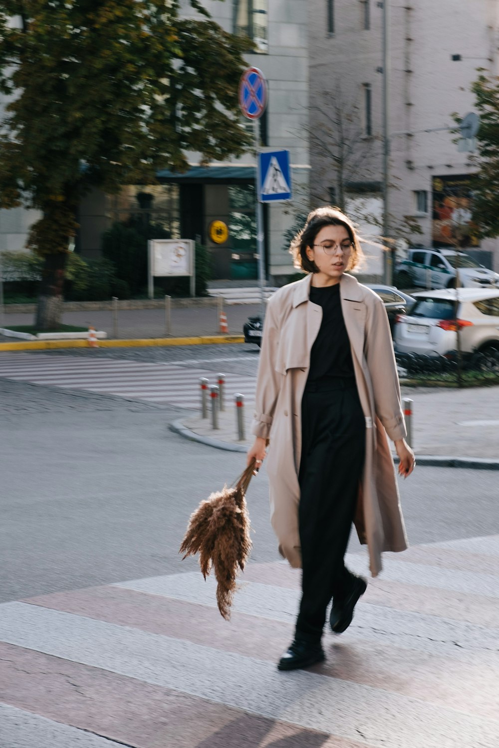 Frau im braunen Mantel mit braunem Besen steht tagsüber auf dem Bürgersteig