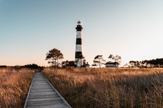 white and black lighthouse near green grass field during daytime