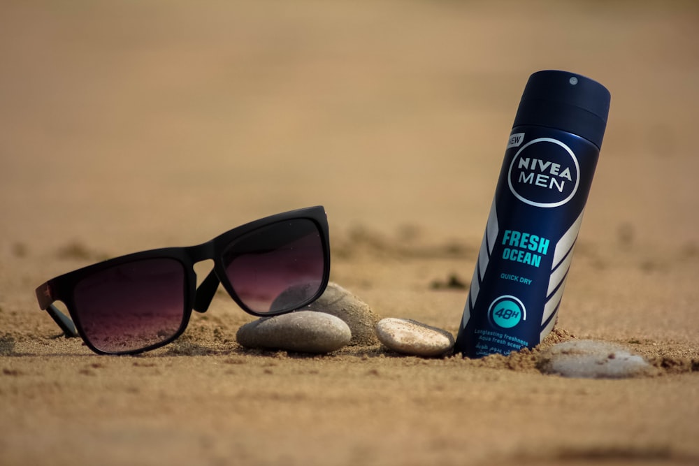 black sunglasses beside nivea men spray bottle on brown sand