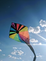A colorful handcrafted kite with unique patterns in a sunny sky.