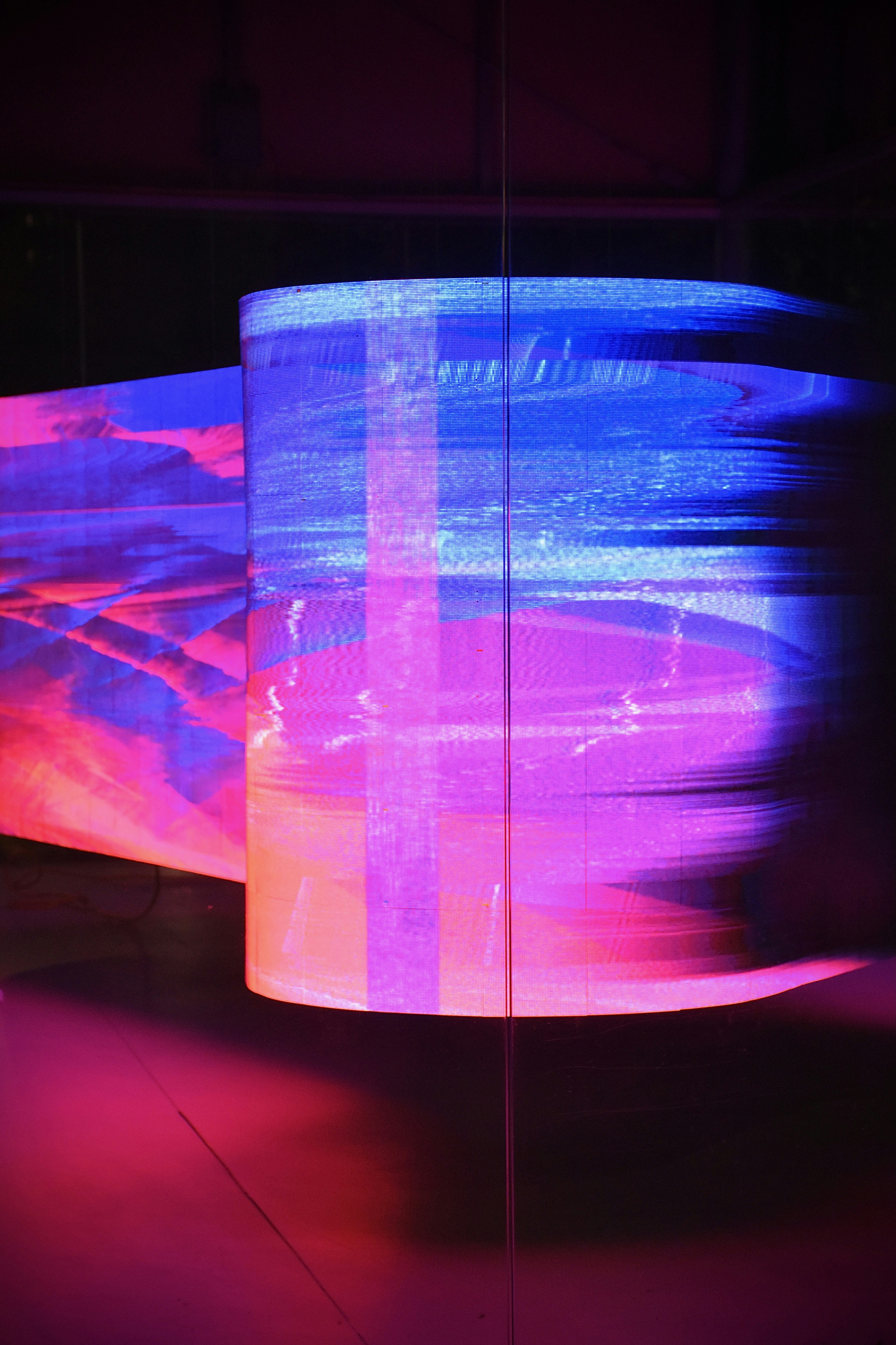 Two large digital screens displaying colorful glitched art.