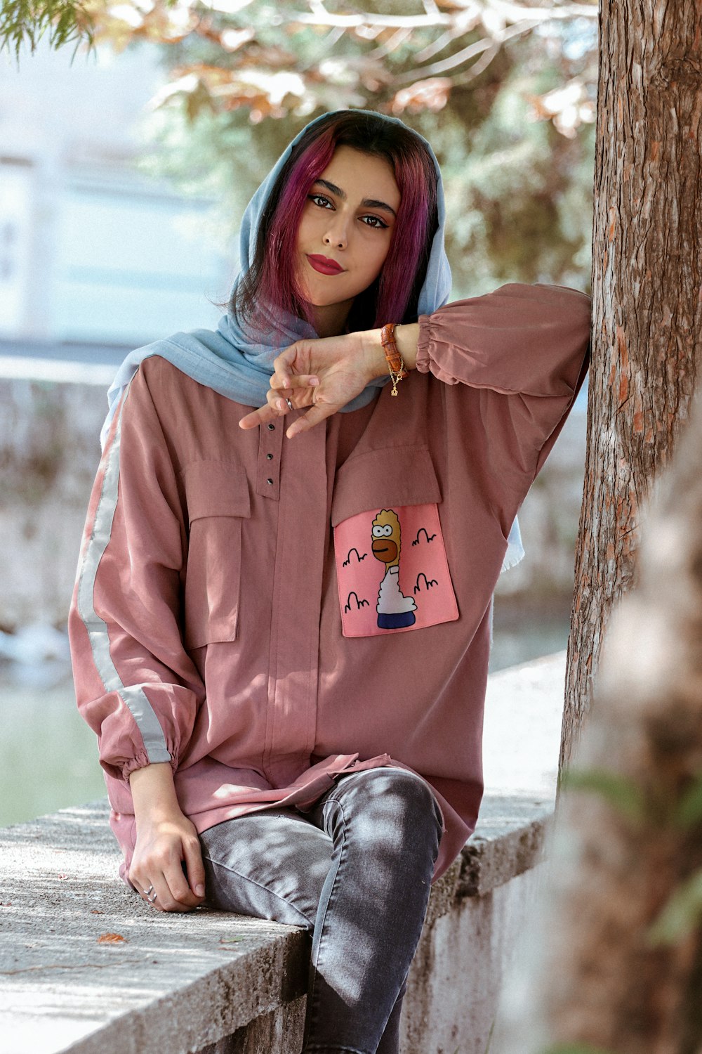 woman in blue long sleeve shirt and black pants sitting on gray concrete floor