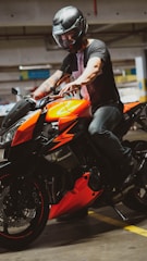 man in black leather jacket riding orange and black sports bike