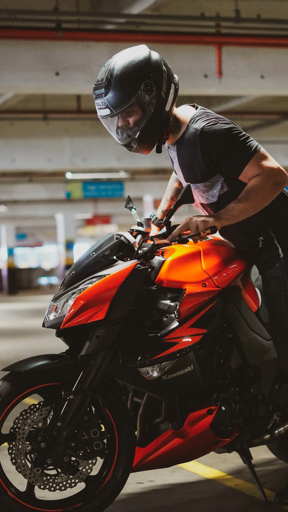 man in black and white t-shirt riding orange and black sports bike during daytime